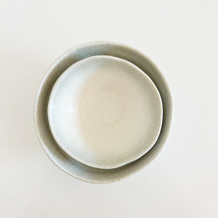 Stack of small and medium Shoreline bowls. Organic shaped ceramic bowls with a creamy white glaze with a soft grey border. Each sold separately.