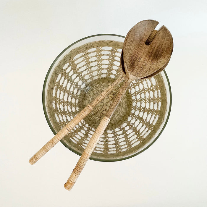Seagrass Serving Bowl is made from recycled mouth blown glass and wrapped in a hand woven natural seagrass cage. It adds beautiful texture to any table. Shown with our wood salad servers. Each sold separately.