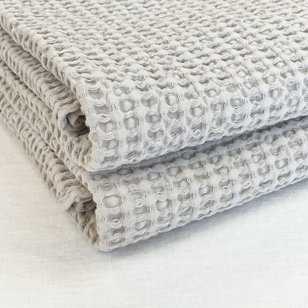 Stack of Simple waffle towels in a warm light grey color. Made by Hawkins NY.  Made in Portugal in a 100% cotton waffle weave. Hand and bath towel each sold separately.