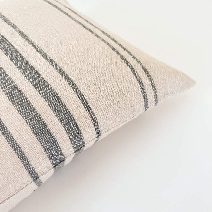 Close up detail of rustic texture on  pillow with navy stripes on an ecru ground.