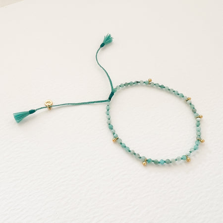 Amazonite bracelet. Shades of soft aqua faceted Amazonite stones mixed with mini gold charms  hand knotted on a aqua yarns. Finished with mini tassels and a pull tab adjuster. One size fits most.