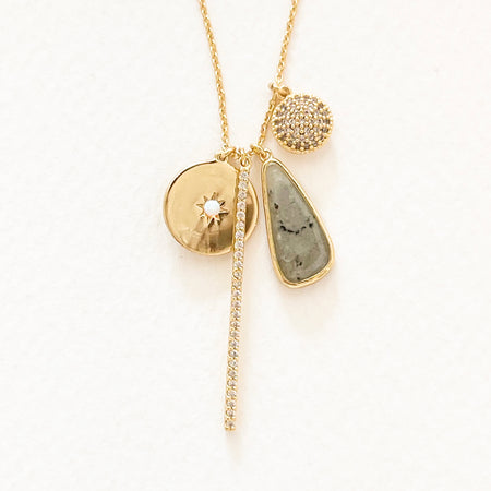 Starlight charm necklace. Delicate gold filled chain with four pendant charms: a gold disc with CZ starburst, a bar encrusted with clear CZ crystals, a semi precious Labradorite tear shape charm and a pave' encrusted gold disc. 20" length with 2" extender.
