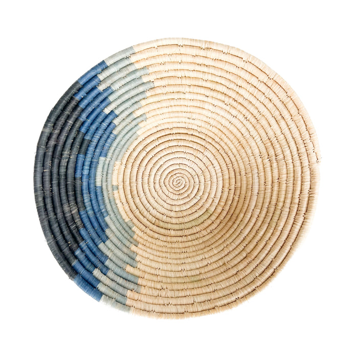 Large coastal blues basket bowl. Sweet grass and raffia are hand woven into coils forming the bowl. Natural raffia with slices of dark to light indigo. Measures 14" diameter 4" depth.