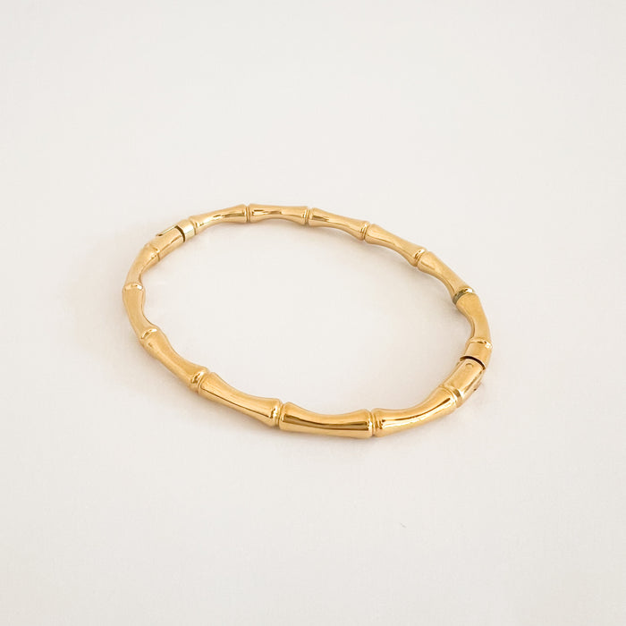 Bamboo bangle in gold finish. Oval bangle in the shape of bamboo with a hinge/clasp closure. Measures 6 7/8" circumference. Water, sweat and tarnish resistant jewelry made by Ellie Vail. Made of hypoallergenic marine grade stainless steel with gold plating.