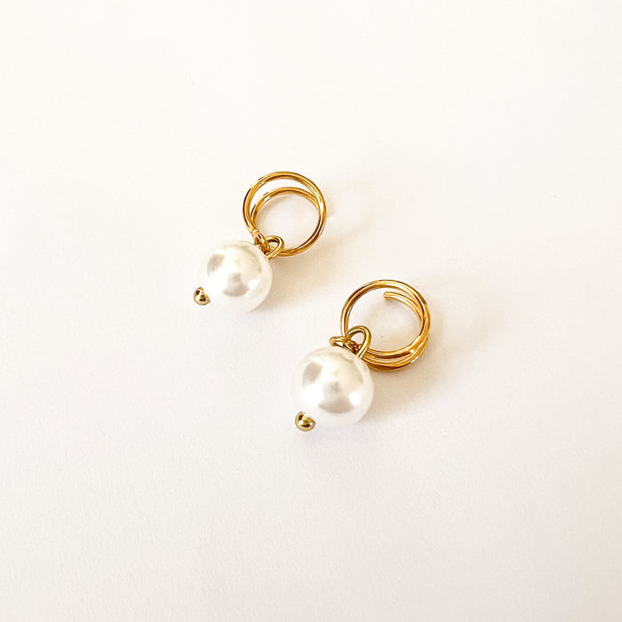 Cove spiral earrings by Ellie Vail. Gold wire spirals  with a solitary white pearl pendant. Sweat, water and tarnish resistant. Made of marine grade stainless steel  with gold plating and natural pearl.
