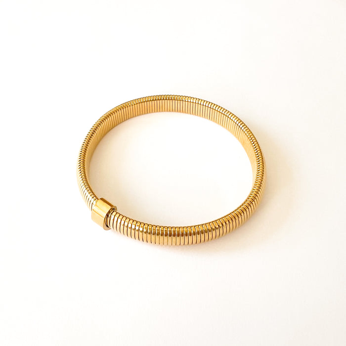 Wren Coil bracelet by Ellie Vail. Gold coil bracelet with a gold bar. 8" circumference. Sweat, water and tarnish resistant. Made of marine grade stainless steel with gold plating.