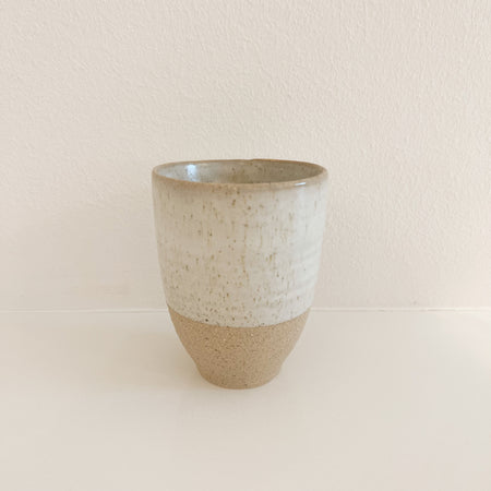 Leche stoneware mug crafted in natural sandstone with the upper half dipped in a creamy white glaze. 4.5" tall 3.25 diameter at rim. Microwave and dishwasher safe. Sold individually.