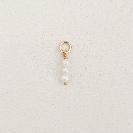 Mini triple pearl charm. Three baby white seed pearls stacked on a gold filled ring. Designed to layer and mix on any of our charm builder necklaces or earrings. Measures 5/8" total length including ring.