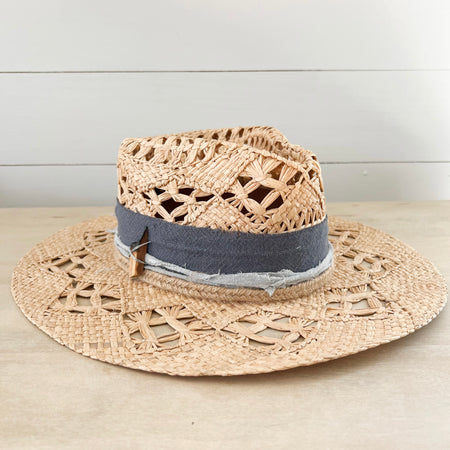 Sea Drifter hat woven in natural palm with an open ornate weave. Crown is wrapped with sea blue cotton gauze strips and a braided jute band. Finished with a chunk of Palo Santo wood. Hand crafted by La Macarena Hats.