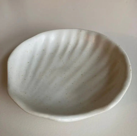 Wabi ceramic dish in a gentle shell shape. Handcrafted in stoneware with a creamy white glaze. Use as a jewelry dish, soap dish or candle tray. Measures approximately 4.25" diameter.