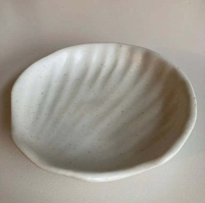 Wabi ceramic dish in a gentle shell shape. Handcrafted in stoneware with a creamy white glaze. Use as a jewelry dish, soap dish or candle tray. Measures approximately 4.25" diameter.