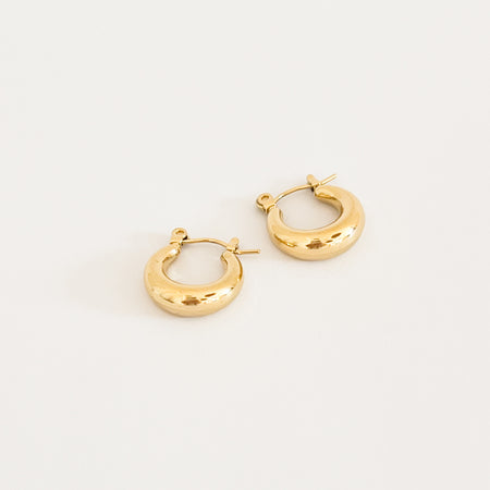 Anastasia huggie hoop earrings. Small scale chunky golden hoops with a "clicker" closure. Measures 5/8" diameter. Water, sweat and tarnish resistant. Made of hypoallergenic stainless steel by Ellie Vail.