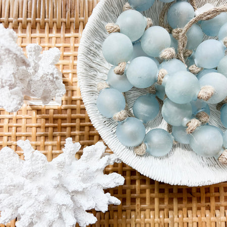 White Reef bowl styled with blue beach glass beads and accompanied by white coral on a rattan shelf. All items sold individually.