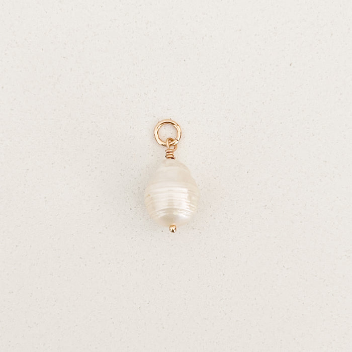Organic shaped white Baroque pearl charm with gold filled fittings. Measures 7/8" length .5" diameter. Designed to fit layer onto our charm builder necklaces, sold separately.