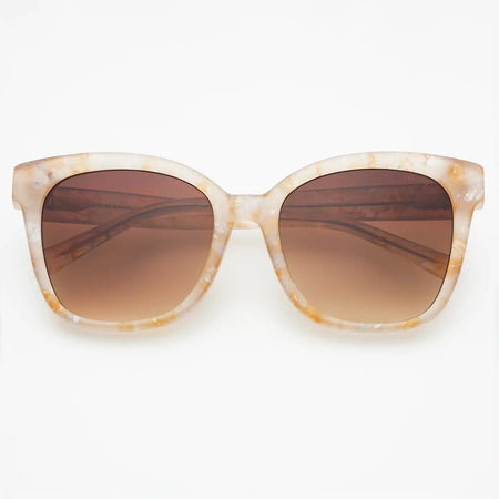 Sunglasses with a soft blush pink tortoise frame and brown lenses on a white background