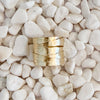 A textured gold ring with a multi-spiral, layered design, resting on a bed of smooth white pebbles. 18k gold over brass. Adjustable, fits size 7-9.
