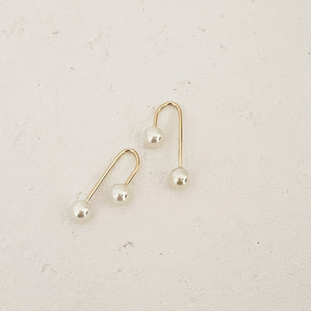 Pair of pearl and gold arch threader earrings. A gold filled arch with a screw on pearl back. 1" length, 3/8" width.