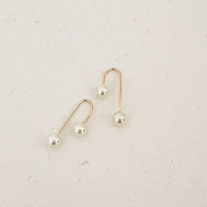 Pair of pearl and gold arch threader earrings. A gold filled arch with a screw on pearl back. 1" length, 3/8" width.