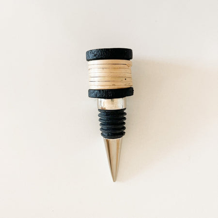 Brisbane bottle stopper made of stainless steel with natural rattan handle and black edges.