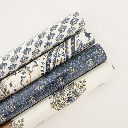 Four rolls of indigo and cream block printed gift wrap. Four different floral and paisley patterns, each roll sold separately. Each roll contains 3 sheets of the same pattern. 28" x 20"