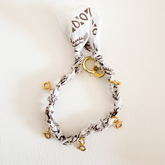 White and brown braided bandana bracelet with five golden spring clasps designed to hold charms.