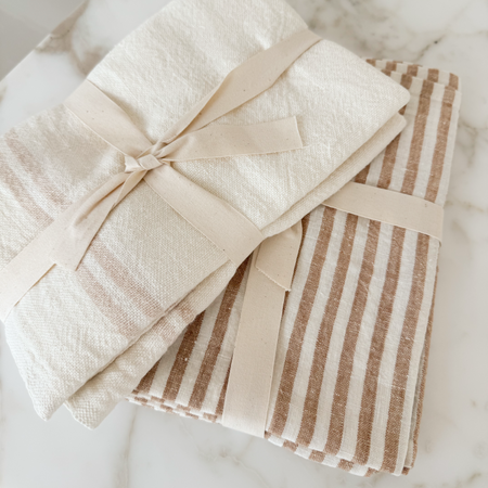 Two stacks of 100% linen tea towel. Brasserie stripe on the left and Tangier bengal stripe on the right. Each sold separatley.