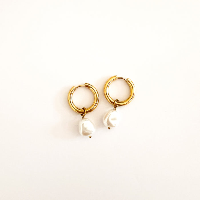 Anya pearl hoop earrings. Pair of 18K gold PVD gold plated clicker hoop earrings featuring a baroque pearl charm. Hoop diameter is 19mm, total length 29mm. Nickel and lead free. Stainless steel base metal.