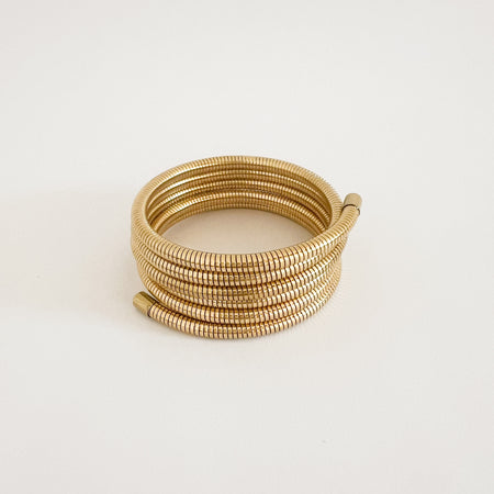 Krishna coil wrap bracelet. Flexible golden coil bracelet that wraps five times around the wrist for a luxe bohemian look. Made of hypoallergenic marine grade stainless steel with gold plating by Ellie Vail. Approximately 7" circumference.