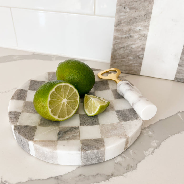 Round tray made in a checkerboard of white and buff grey marble. Concave surface prevents juice from dripping. 8" diameter x 1"high. Styled with limes, and a marble and brass bottle opener, not included.