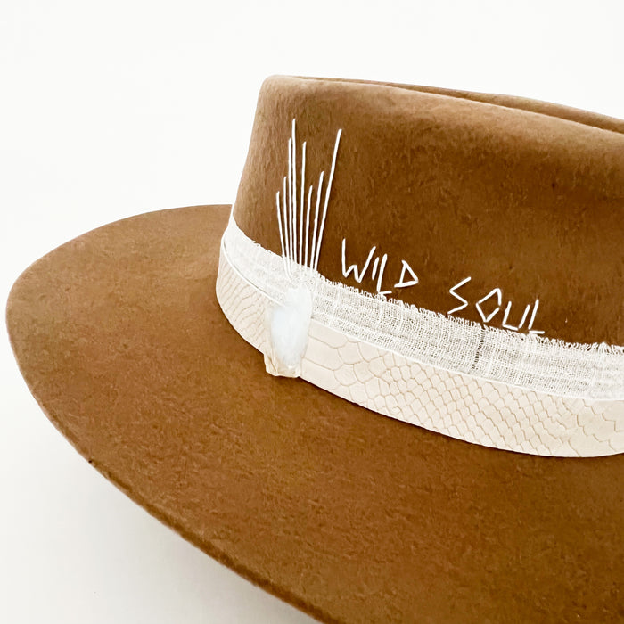 Wild Soul embroidery in white on a tobacco colored fine wool hat. Hat is wrapped with an ivory snakeskin band and white cotton gauze ribbon.