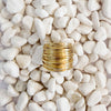 A gold ring made of a cluster of finely wrapped gold wires sitting on white pebbles. 18k gold over brass.