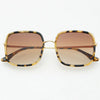 Sunglasses with a brown tortoise frame and softly tinted brown lenses on a white background.