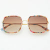 Sunglasses with pink toned tortoise frame and softly tinted brown lenses on a white background.