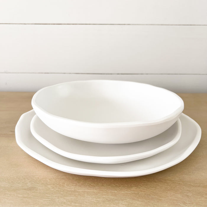 "Cloud" table setting. Dinner plate, salad plate and pasta bowl in white melamine. Part of the Nube collection by Beatrix Ball featuring modern organic silhouettes with a matte white finish. Each piece sold separately.