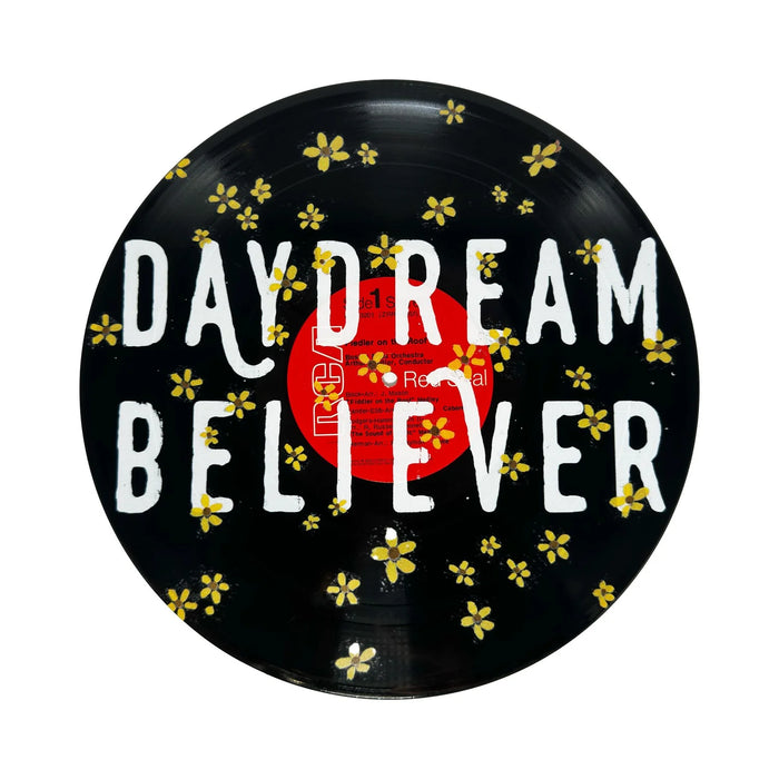 Vinyl record with 'Daydream Believer' text and floral decorations on a white background