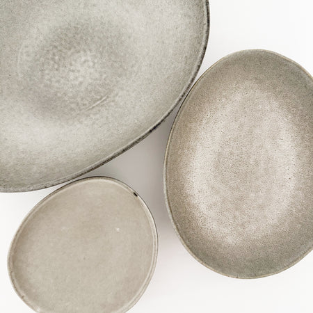 Three oval shaped stoneware bowls in an oyster grey glaze. Each piece sold separately.