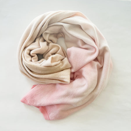 Sunset + Sand dip dyed cashmere wrap. Hand dyed in a mix of soft sand, white and pale blush pink. Swirls of color inspired by the sunset. Made of 100% cashmere jersey. 32" x 90".