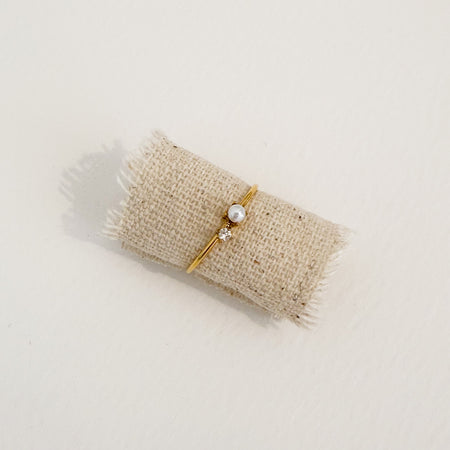 Delicate gold ring adorned with a tiny clear CZ stone and a delicate white Mother of Pearl. Water, sweat and tarnish resistant.