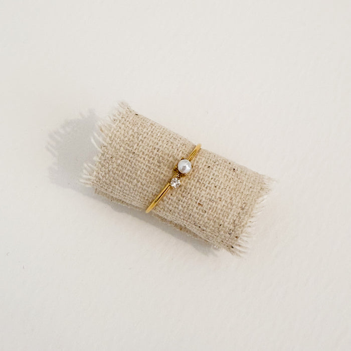 Delicate gold ring adorned with a tiny clear CZ stone and a delicate white Mother of Pearl. Water, sweat and tarnish resistant.