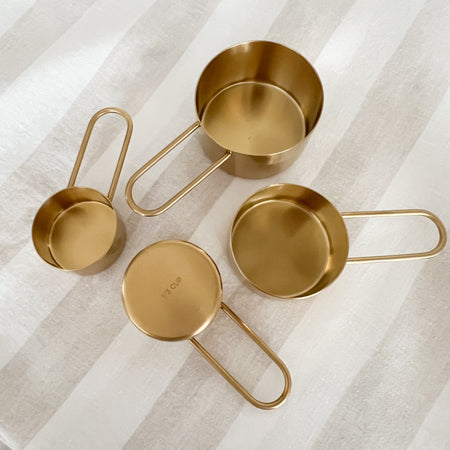 Set of 4 measuring cups with sleek rounded handles. Made of stainless steel with a PVD coated brass finish. Includes a 1 c, 1/2c, 1/3c and 1/4c. Set comes in a drawstring canvas bag.