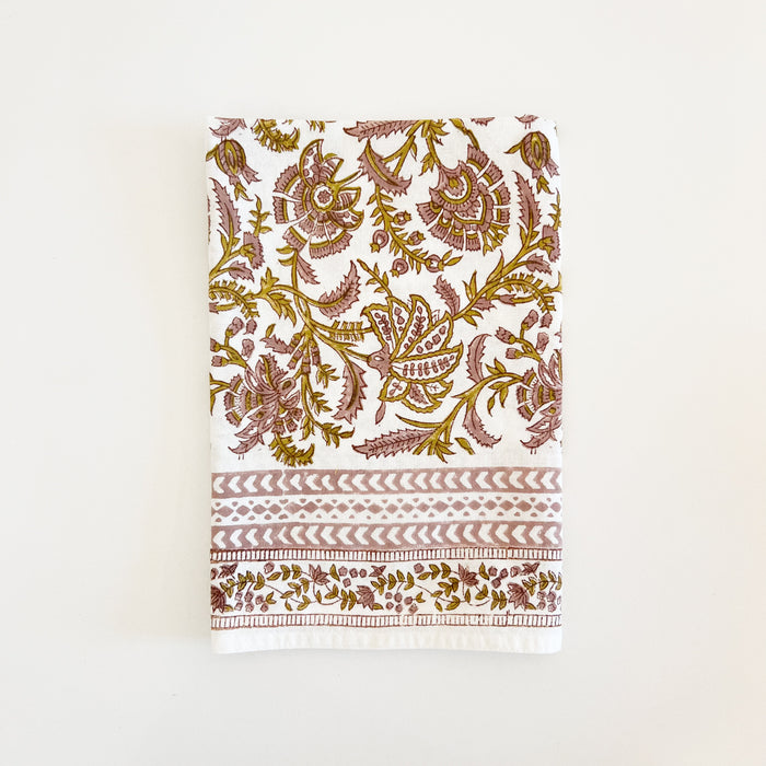 Marigold woodblock print napkin. 20" square cotton napkin with a swirl of flora and vines printed using a dusty rose and ochre dye on white. Printed border frames all four edges. Each sold individually. Hand printed by artisan printers in India.