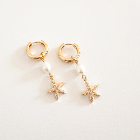 Sea Star + Pearl hoop earrings. 18k gold clicker hoops with a white pearl and golden sea star pendant. Charm is removable and hoops can be worn alone. Hoop diameter .5", 1.75" length.