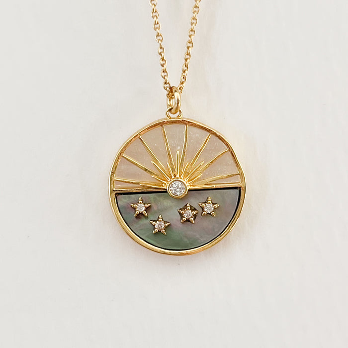 Round Sunset Charm necklace made of white and smoke mother of pearl with a gold inlay setting sun. Tiny CZ crystal stars glitter on the surface. Hand crafted by TAI Jewelry.