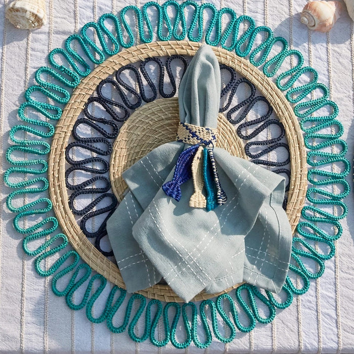 Coastal inspired table setting featuring a woven fish napkin ring, woven placemat and napkin. Fish napkin rings are handwoven in Toquilla palm by aritsans in Columbia. Sold as a set of 2. Other items sold separately.