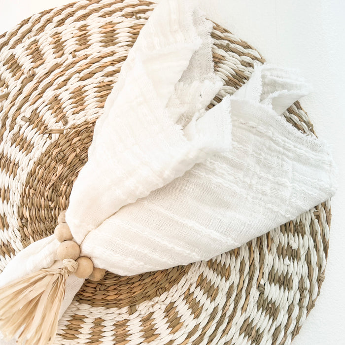 White Serena gauze napkin with wood ball napkin ring and Uma seagrass placemat. Each sold separately.