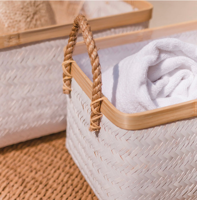 White bamboo storage baskets handwoven in a herringbone weave. Rectangular shape with natural bamboo edge and rope handles.