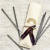 Package of 12 hand rolled Grey Copal incense sticks. Packaged in hand made paper envelope with hand dyed plum ribbon and brass charm.