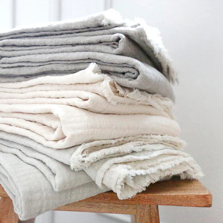 Stack of Hermosa gauze throws by Pom Pom at Home. Available in two colors, ocean and cream. Made in a soft double faced gauzy weave. 77% cotton 23% linen. Perfect for a beach house. 60 x 90 inches.