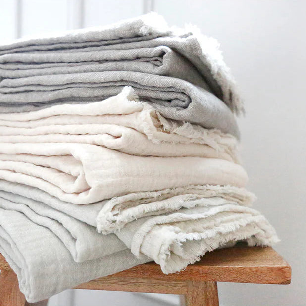 Stack of Hermosa gauze throws by Pom Pom at Home. Available in two colors, ocean and cream. Made in a soft double faced gauzy weave. 77% cotton 23% linen. Perfect for a beach house. 60 x 90 inches.