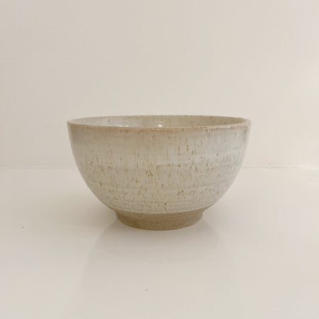 Leche stoneware bowl. Sand colored stoneware bowl glazed in a milky white glaze with speckles of amber. Measures 6.5" diameter, 3.5" height. Microwave and dishwasher safe.